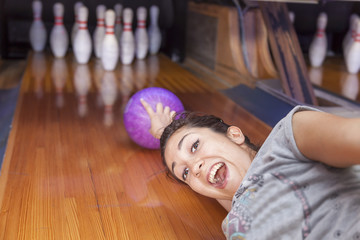young woman sliding down a bowling alley