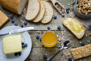 Breakfast with honey in glass jar on natural wooden table.