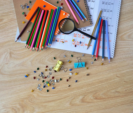 Magnifying glass, colored pencils, buttons and calendar on the wooden surface.