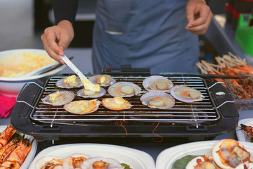 Man cooking the scallops and other seafood on grill barbecue