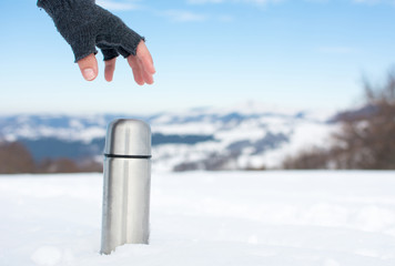 Man holding thermos in on a snowy mountain