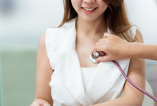 Doctor using stethoscope to exam woman patient heart
