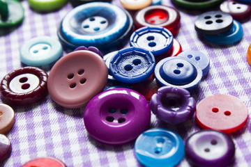 A lot of bright colored buttons on the fabric, sewing.