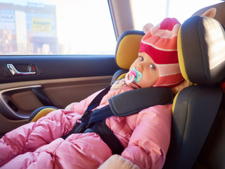 Portrait of cute toddler girl sitting in car seat. Child transportation safety