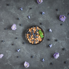 Healthy breakfast with muesli and blueberry on stone background. Flat lay, top view