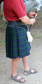 man with kilt  while playing the bagpipes