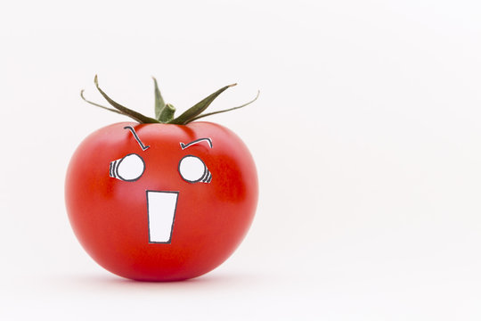 A single fresh red tomato with scared face in front of white background