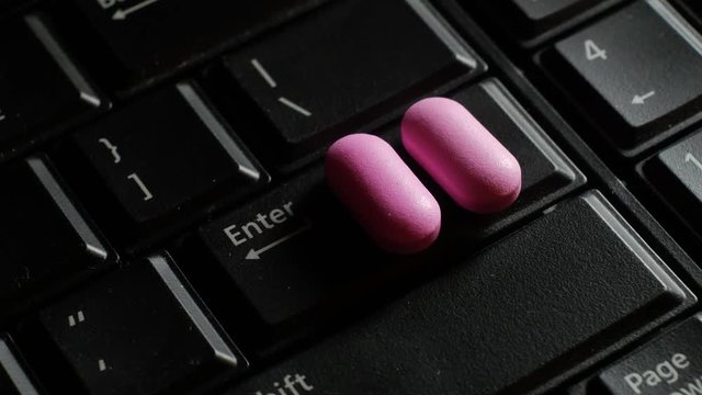 Two pills on keyboard - addict on a computer concept. Computer sick. Technology kills people. Slider move stops on enter key.