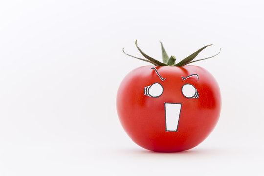 A single fresh red tomato with scared face in front of white background