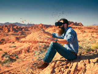 cool bearded guy wearing vr goggles in nevada desert with digita