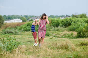 Pregnant woman walking countryside with her son.