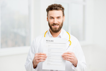 Doctor in uniform holding resume for job hiring in the white interior