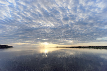 Obraz premium View of the golden sunset on the river with clouds and the Sun reflected in it, Volga, Russia