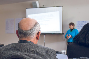 Speaker giving presentation in lecture hall. Participants listen