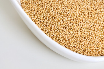 Amaranth grain in bowl on white background. Copy space