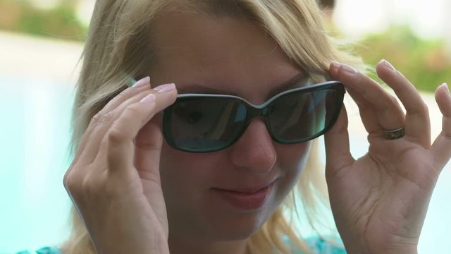 Sexy blonde woman removes sunglasses and wink