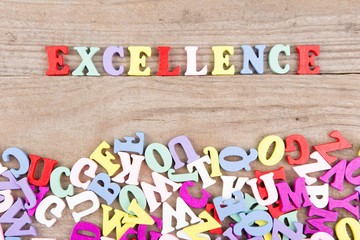 Text "Excellence" of colored wooden letters on a wooden background