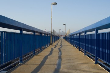 High lamps lined by blue railing and sky in background