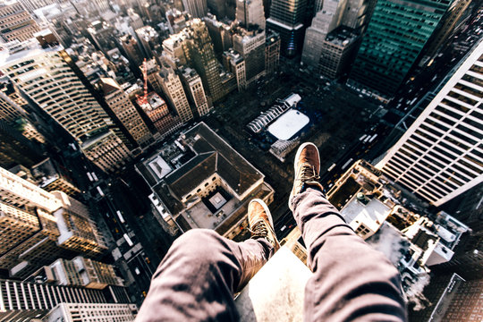 Point of view image of persons legs on top of skyscraper