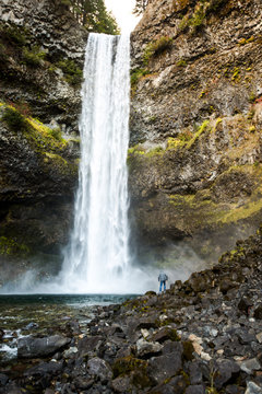 Person standing by huge waterfall