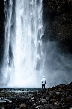 Rear view of person standing by waterfall