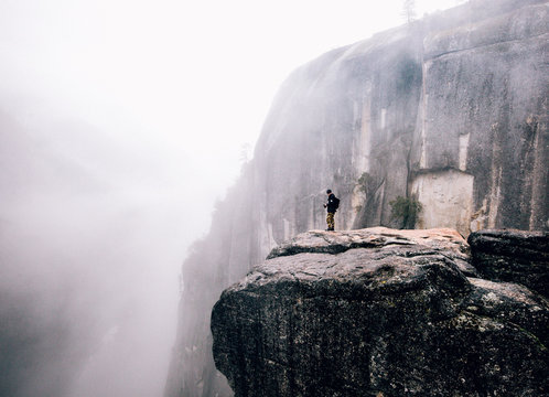 Man standing on cliff in mist
