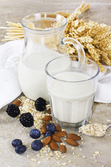 Glass of ecological oat milk with berries on wooden desk