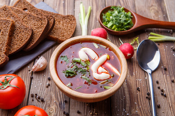 Beet soup in wooden plate with vegetables