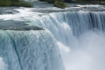 The bright blue water of Niagara Falls flows down the river and over the waterfall in spring