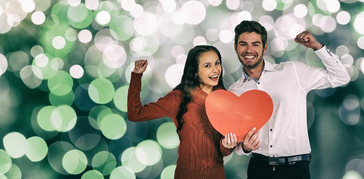 Composite image of cheerful couple holding paper heart