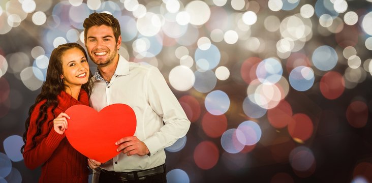 Composite image of happy couple holding paper heart