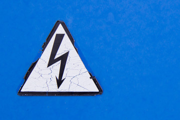 Cracked sign high voltage on blue wall