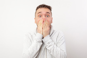 Surprised young man in shock covers his face