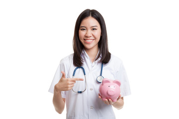 Young Asian female doctor point to a pig bank coin.