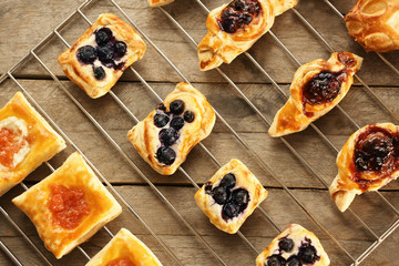 Sweet tasty pastries on baking grid against wooden background