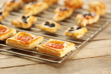Sweet tasty pastries on baking grid against wooden background