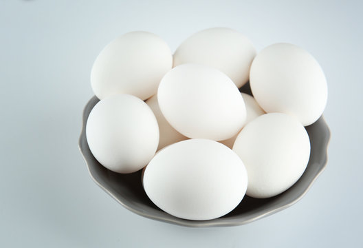 Raw eggs in bowl on white background
