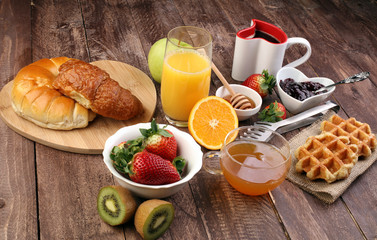 breakfast on table with waffles, croissants, coffe and juice