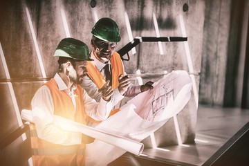 Architects standing on staircase discussing with blueprint