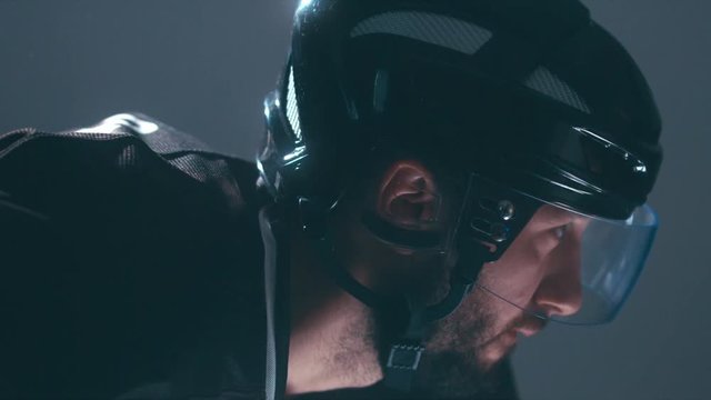 CU Caucasian male ice hockey player in black uniform preparing for a face-off puck drop. 4K UHD 60 FPS slow motion. RAW edited footage