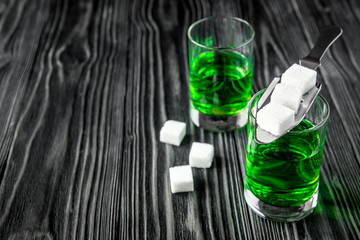 absinthe with sugar cubes and spoon on wooden background