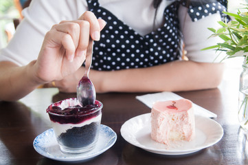 Woman sitting eating double cakes with spoon.