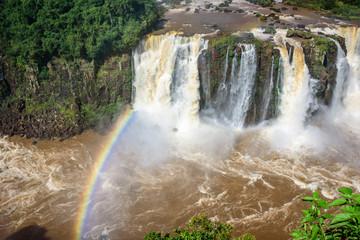 Rainbow and view of cascading water of Iguazu Falls with extensive tropical forest and raging river in Iguacu National Park, UNESCO World Heritage Site, Foz de Iguacu, Parana State, Brazil