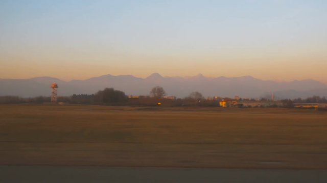 Aircraft taking off and sunset landscape (POV) from Bergamo Orio al Serio Airport near Milan in Italy