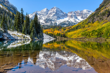 Maroon Bells and Maroon Lake - A wide-angle autumn midday view of snow coated Maroon Bells reflecting in crystal clear Maroon Lake, Aspen, Colorado, USA. - obrazy, fototapety, plakaty