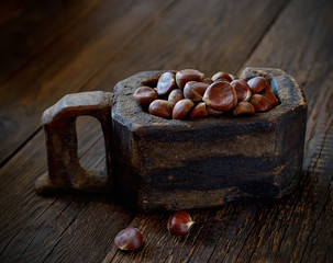 old wooden bucket and chestnuts on a wooden background. rustic style