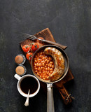 Breakfast in the pan, beans and sausages on a dark background