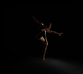 Naklejka premium Graceful girl dancing emotionally in dark studio