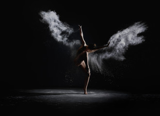 Slender girl dancing in white dust cloud