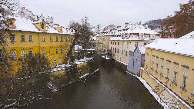 Canal and watermill near Charles Bridge in Prague under the snow in winter